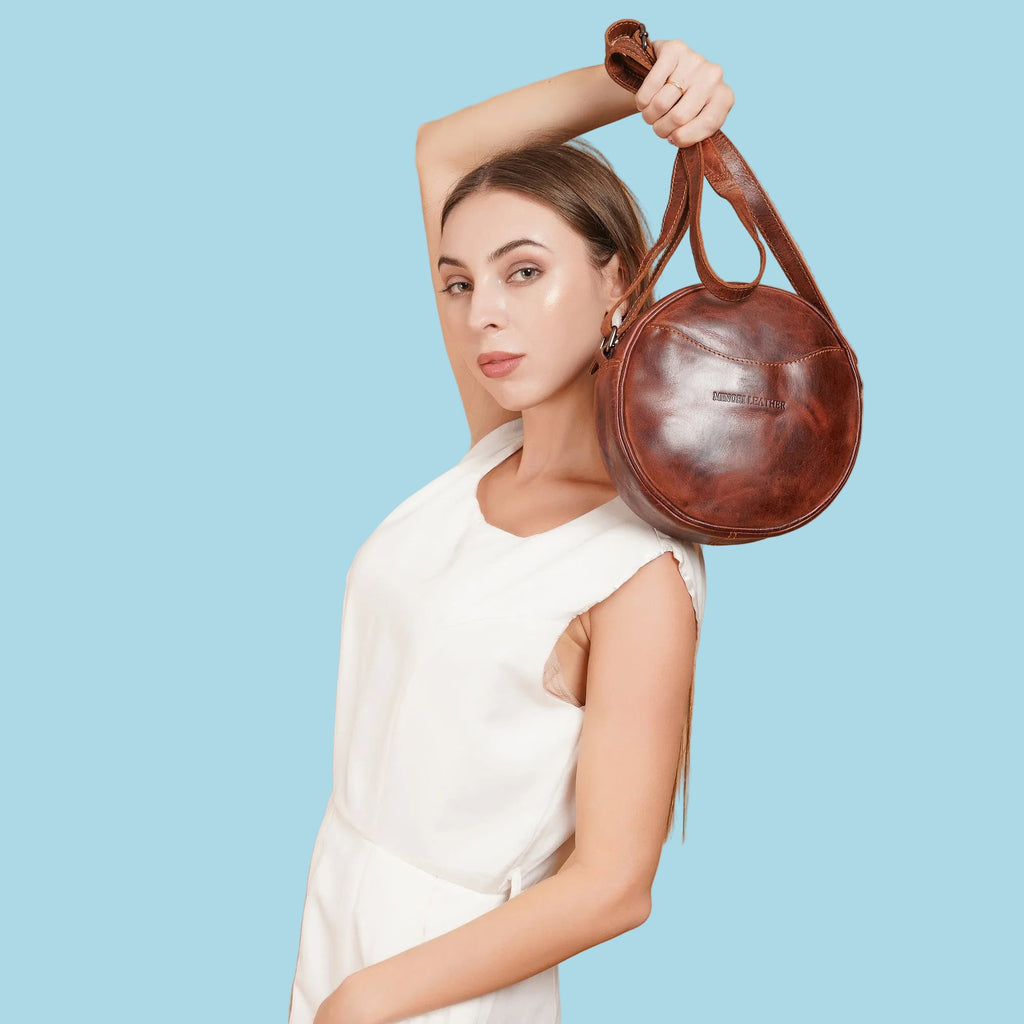Minori Leather Luna round crossbody bag in chestnut and brown hair-on leather, featuring a compact design and adjustable strap.